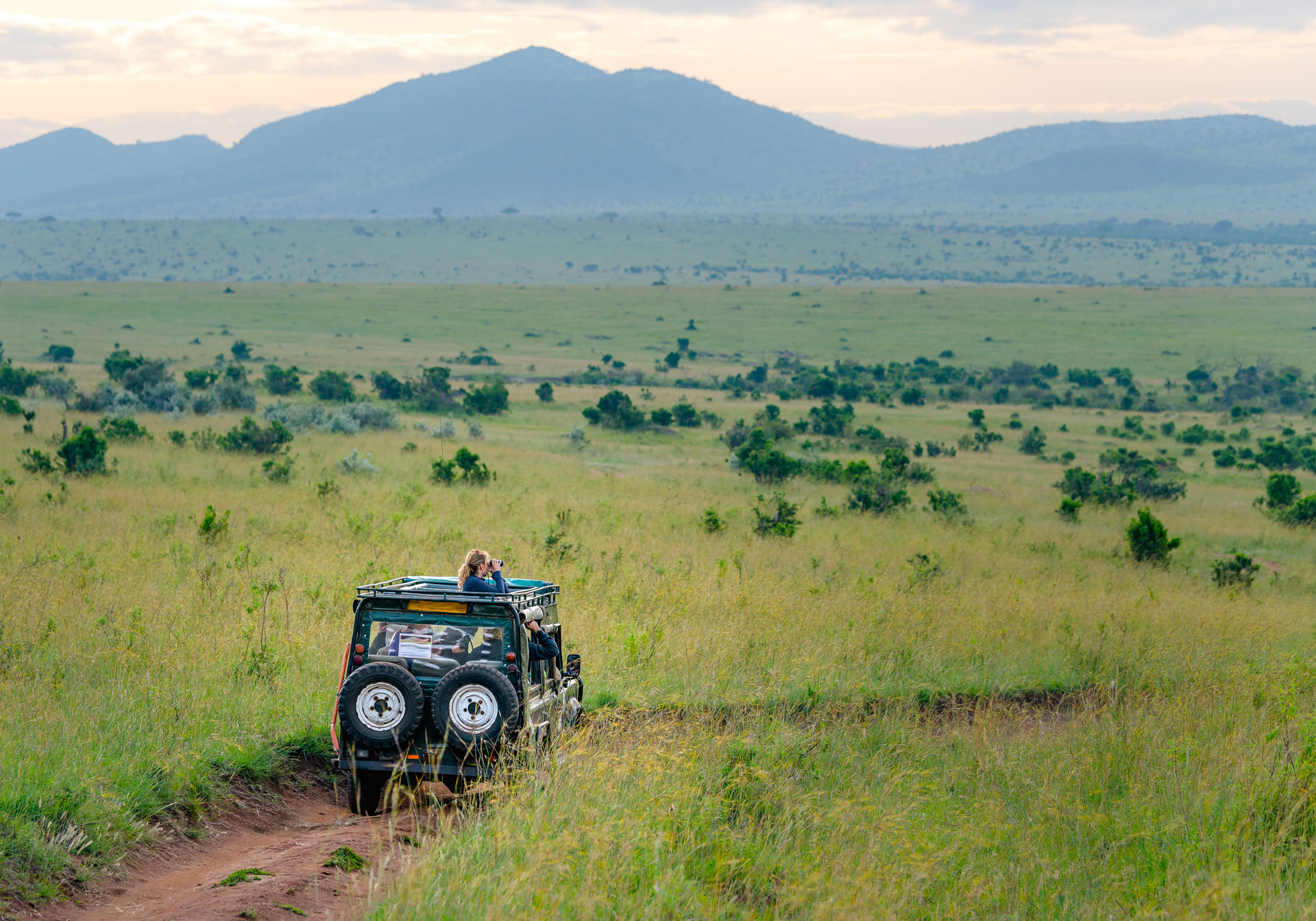 Wide Maasai Mara landscape with safari vehicle